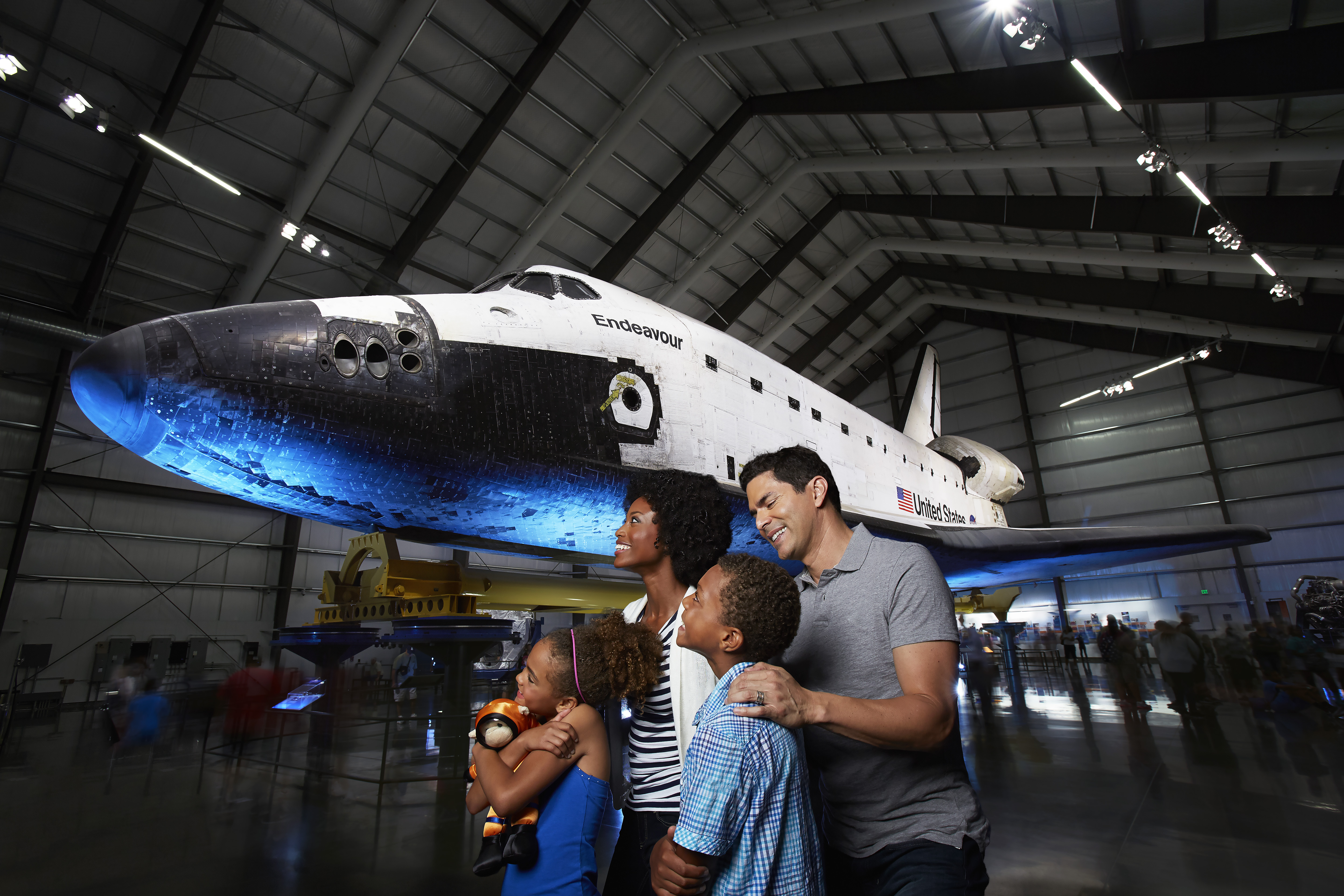 A diverse family group enjoys the space shuttle Endeavour display in the Samuel Oschin Pavilion.