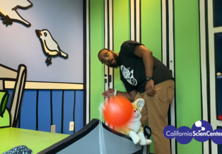 Educator Reggie testing balloon rocket in the Family Discovery Room