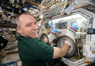 Mission Specialist Drew Feustel performs an experiment on the International Space Station.
