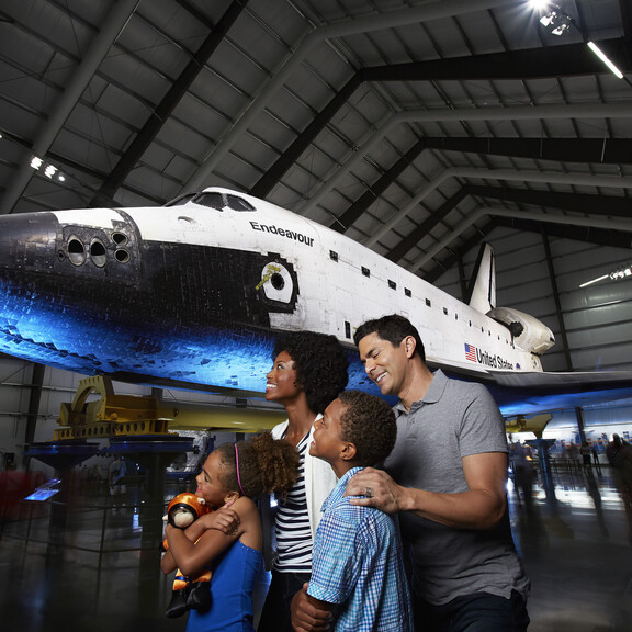 A diverse family group enjoys the space shuttle Endeavour display in the Samuel Oschin Pavilion.
