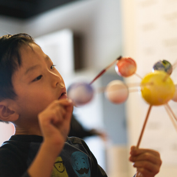 Young boy painting solar system model