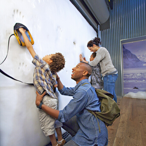 Family touching ice wall inside Ecosystems Poles gallery