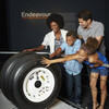 A diverse family touches space shuttle tires in an Endeavour exhibit.