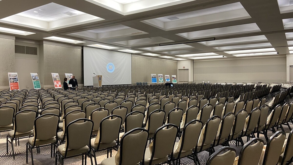 Theater style seats fill Loker Conference Center facing central stage for All Staff Meeting