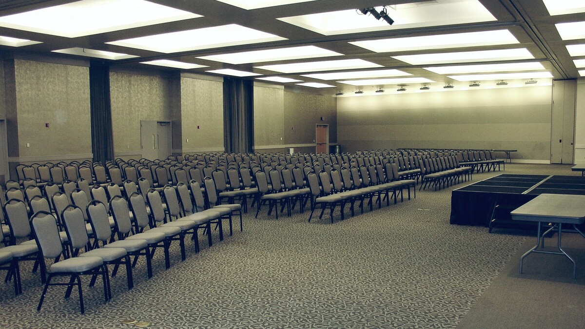 Theater style seats fill Loker Conference Center facing central stage for meeting