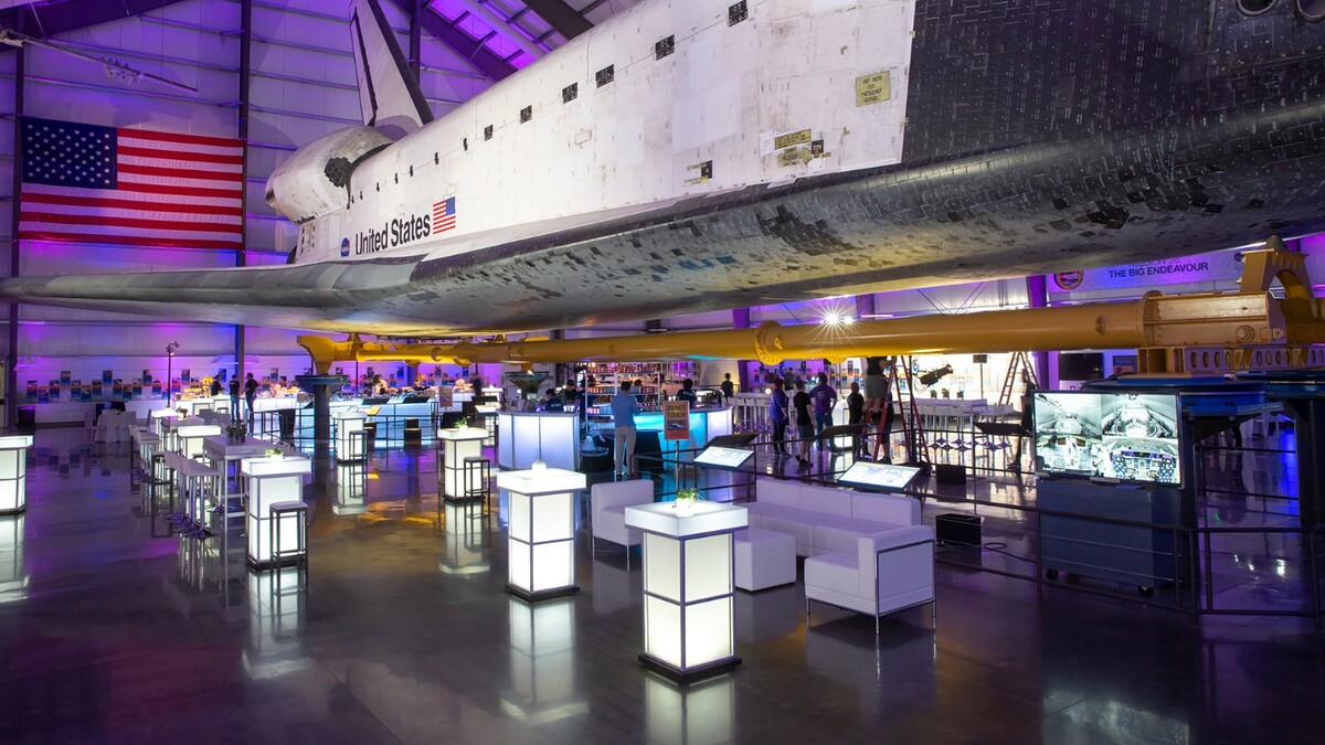 Long shot of the Space Shuttle Endeavour above glowing cocktail tables and white lounge furniture for a private event