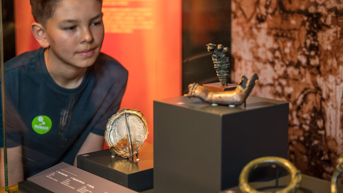 Member looking at artifacts like Inscribed Silver Plate in Angkor: The Lost Empire of Cambodia Exhibition