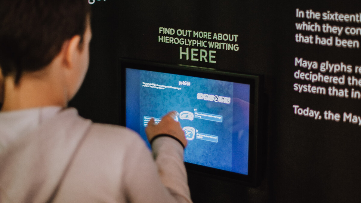 Young guest interacts with touch screen that teaches guests about Mayan hieroglyphic writing.