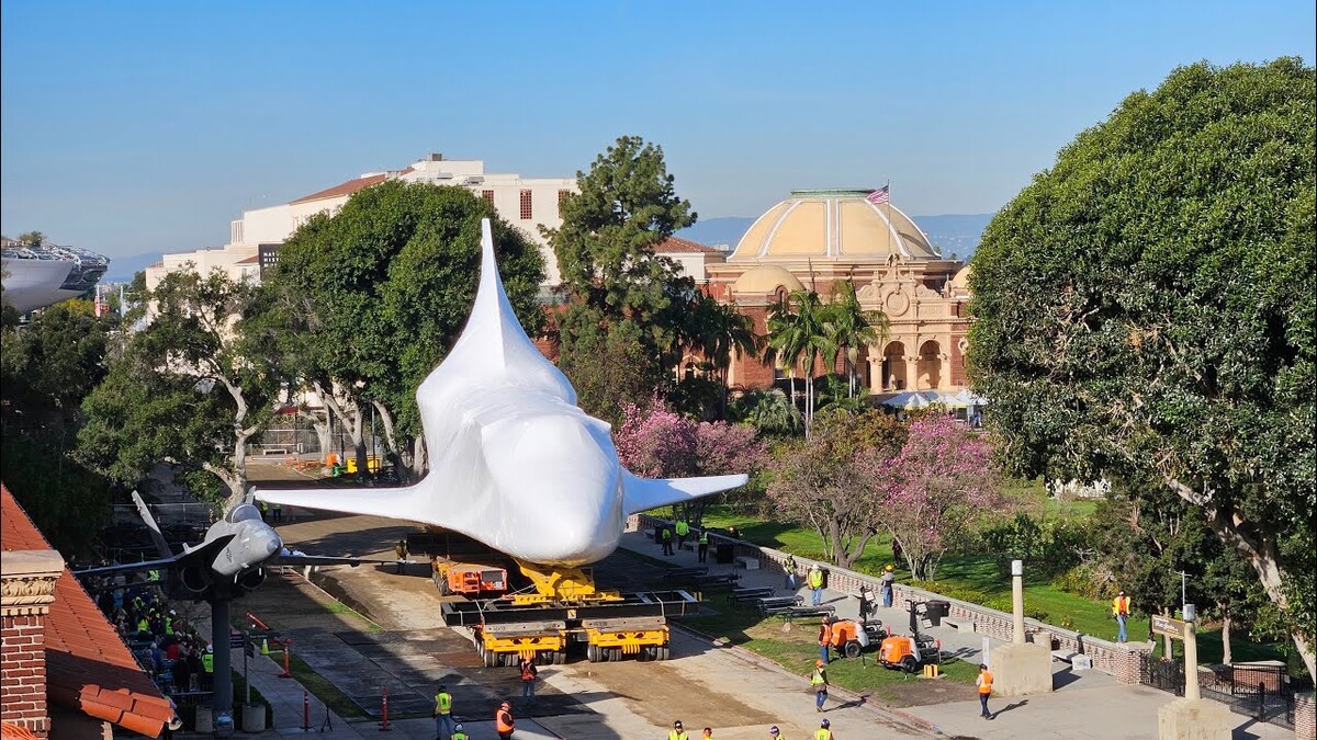 Space shuttle orbiter Endeavour, covered in white shrinkwrap, being transported down a street