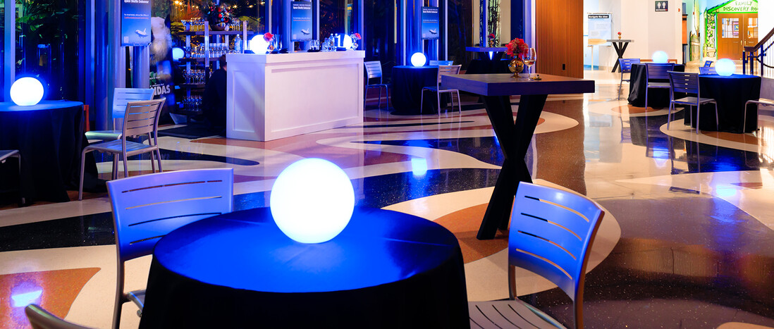 Night cocktail reception in Ecosystems atrium with intimate table groupings and glowing orb centerpieces
