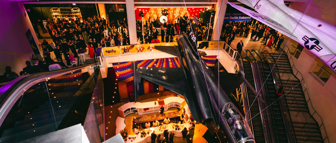 Aerial view of carnival themed cocktail party in the Ahmanson Building with purple and amber lighting at dusk