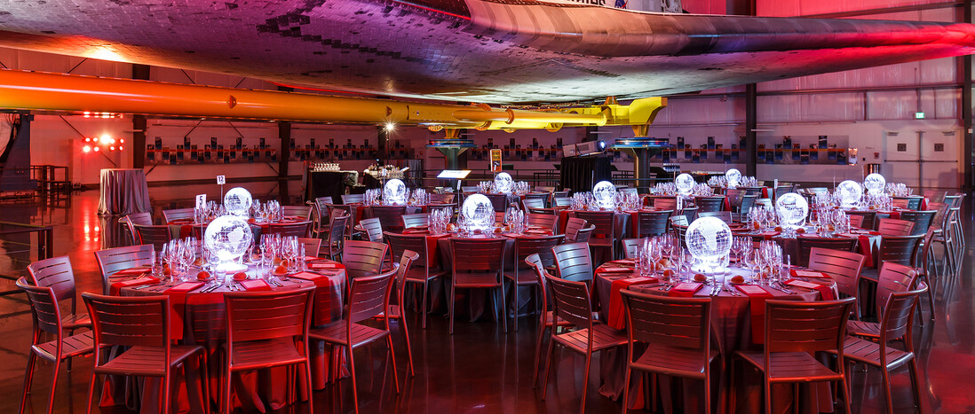 Seated Dinner under the Samuel Oschin Pavilion lit deep red with glowing globe centerpieces