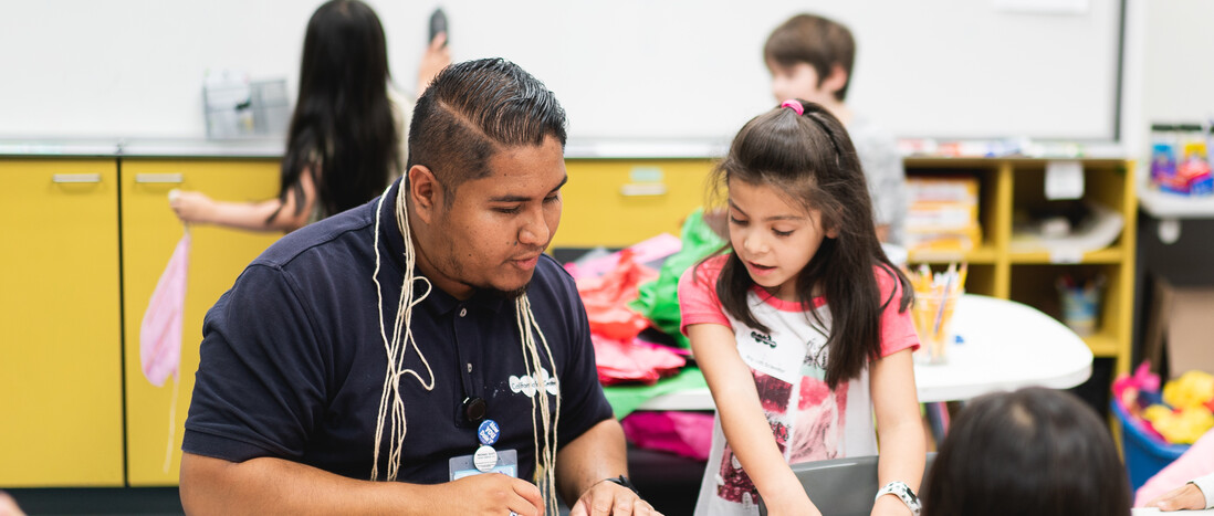 Science Center educator assisting young girl with activity
