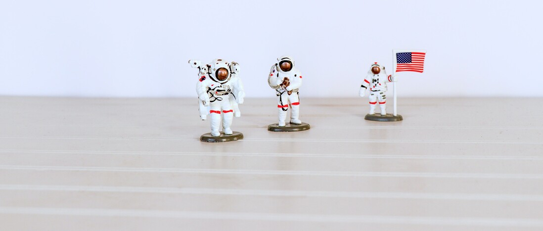 Three US astronaut plastic toys on light tabletop
