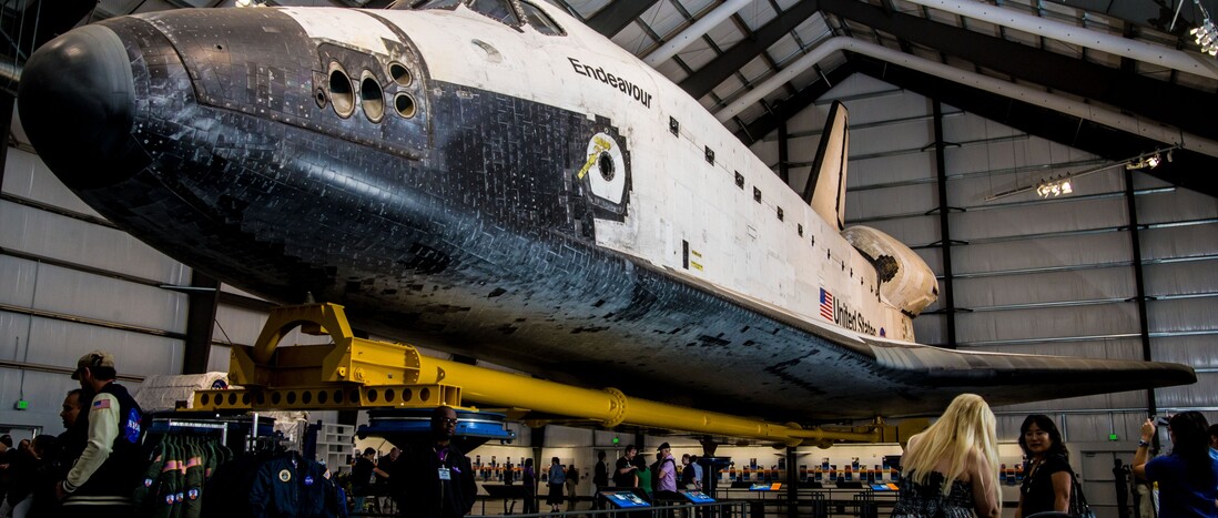 Guests walk around and under admiring space shuttle Endeavour on display at the California Science Center.