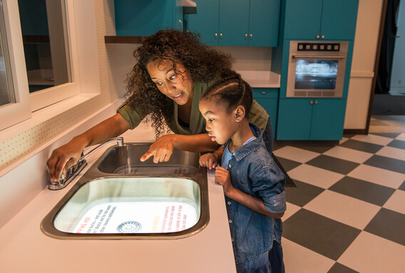 An adult and child read a lit graphic in a kitchen sink.